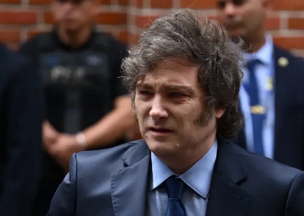 Javier Milei com expressão confusa, olhando para o lado, vestindo terno e gravata