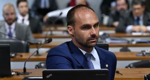 Eduardo Bolsonaro sentado, perto de computador, sério