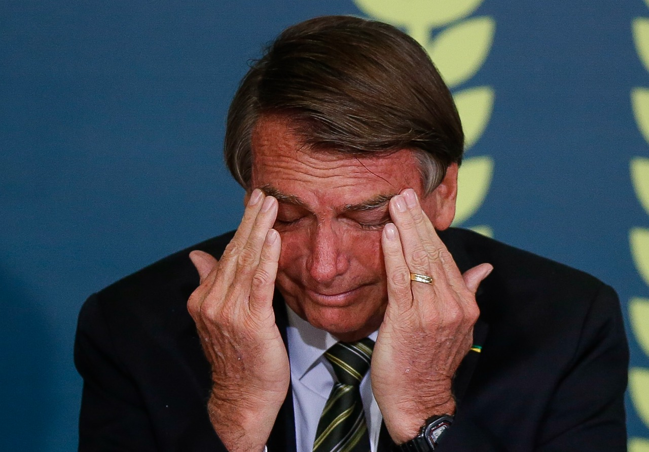 ex-presidente Jair Bolsonaro cabisbaixo, com cara de choro e mãos no rosto