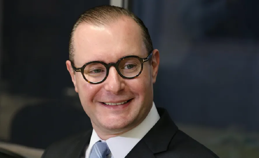 ministro Cristiano Zanin de óculos, sorrindo, em close, sem olhar para a câmera