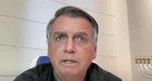 O ex-presidente Jair Bolsonaro (PL) de roupa de frio preta, falando sem olhar para a câmera, em close