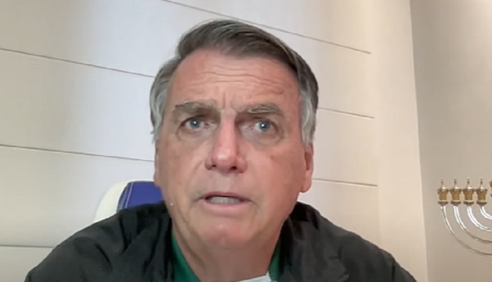 O ex-presidente Jair Bolsonaro (PL) de roupa de frio preta, falando sem olhar para a câmera, em close