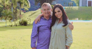 Itamar Serpa e Monique Elias em pé, abraçados, sorrindo para foto em campo aberto