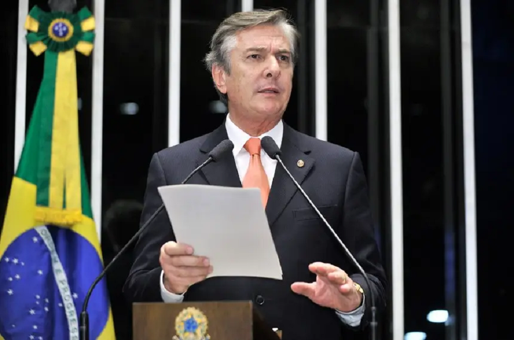 ex-presidente Fernando Collor de Mello falando em microfone, de terno e gravata, com papel na mão, em pé no plenário