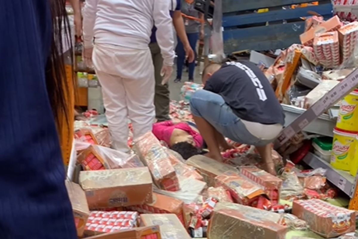 Mulher em meio a caixas de leite condensado, sendo socorrida