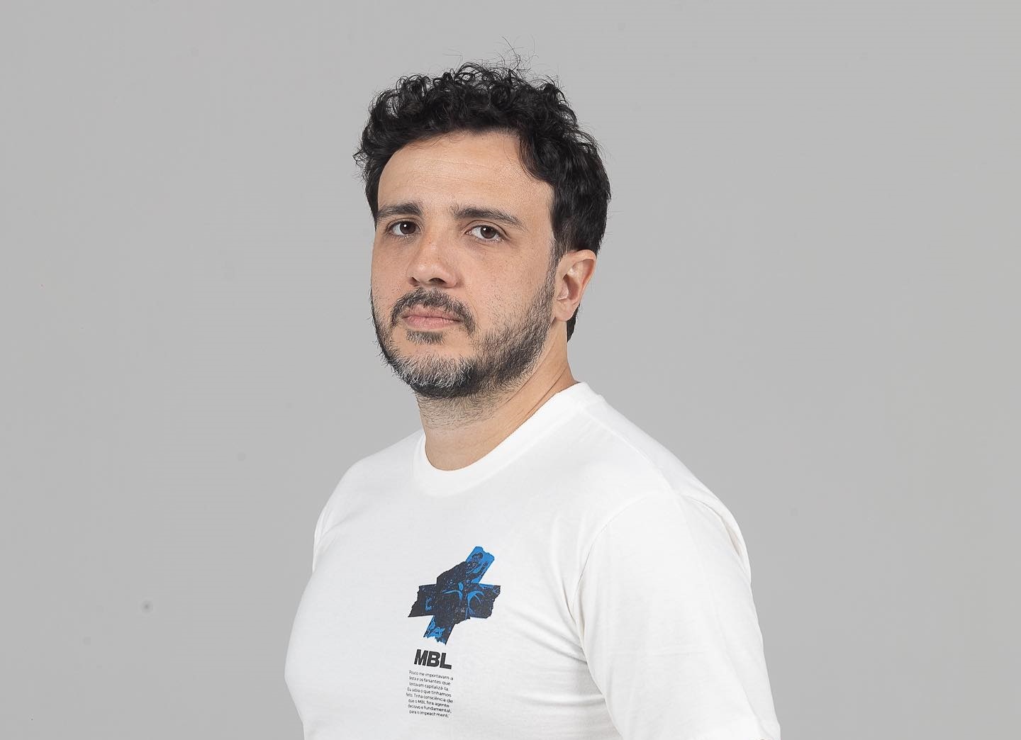 O líder do Movimento Brasil Livre (MBL), Renan Santos, de camiseta branca, olhando para a câmera, sério