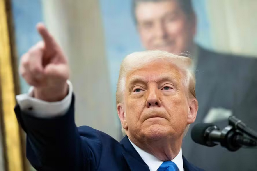 Donald Trump, presidente dos EUA, sério, apontando pra frente, sem olhar para a câmera