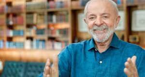 presidente Luiz Inácio Lula da Silva (PT) de roupa social azul, sorrindo para foto com os braços abertos