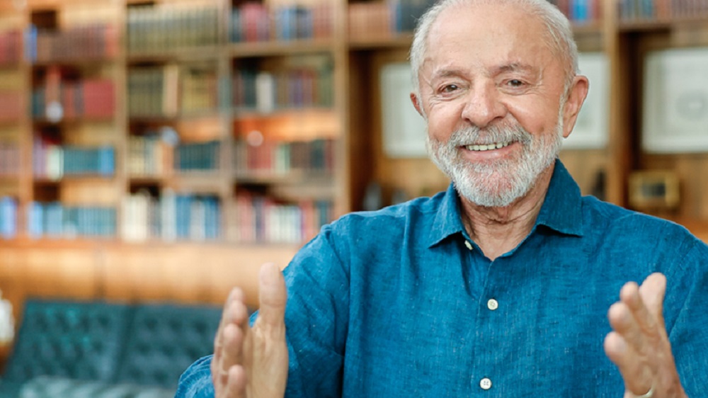 presidente Luiz Inácio Lula da Silva (PT) de roupa social azul, sorrindo para foto com os braços abertos
