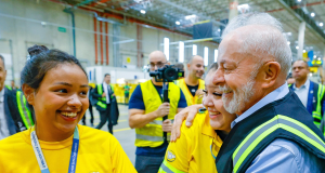 Lula de perfil cumprimentando funcionárias no Centro de Distribuição do Mercado Livre, as três pessoas sorrindo