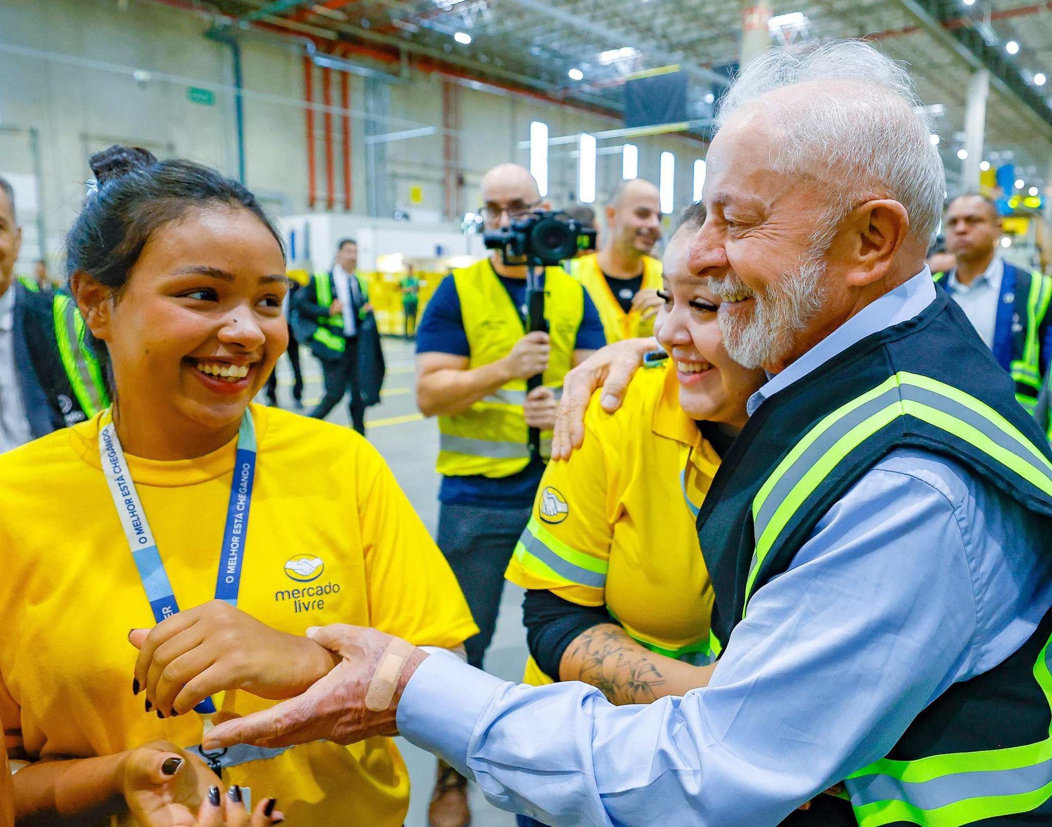Lula de perfil cumprimentando funcionárias no Centro de Distribuição do Mercado Livre, as três pessoas sorrindo