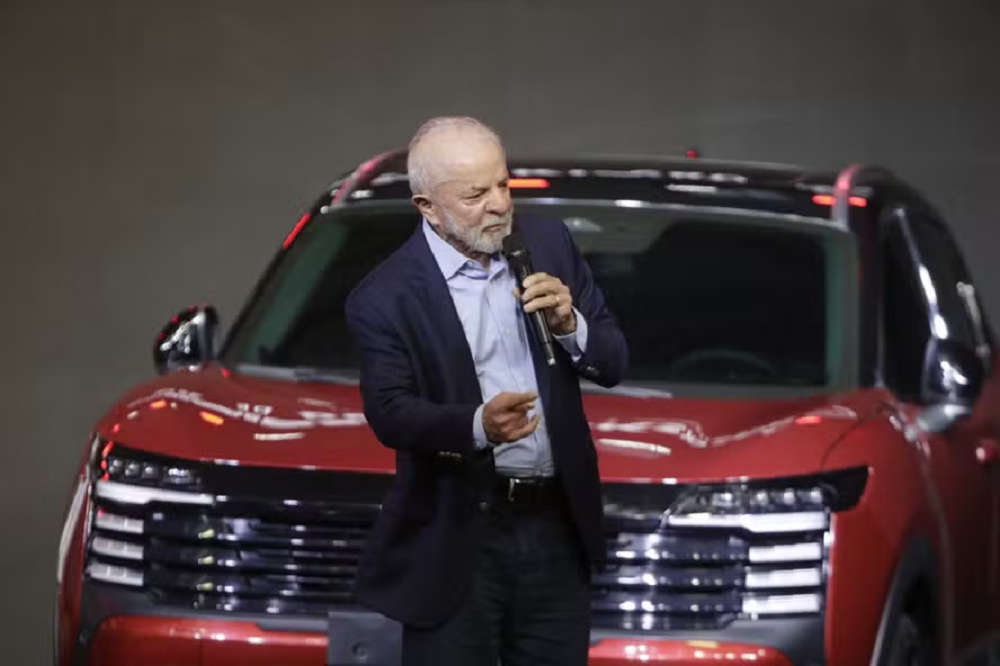 O presidente Luiz Inácio Lula da Silva (PT) falando em microfone e gesticulando, na frente de carro vermelho