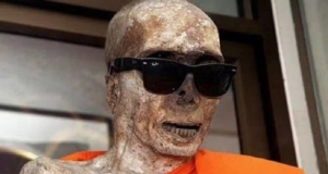 Monge budista que foi mumificado em templo no Japão, coberto com tecido laranja e óculos escuros