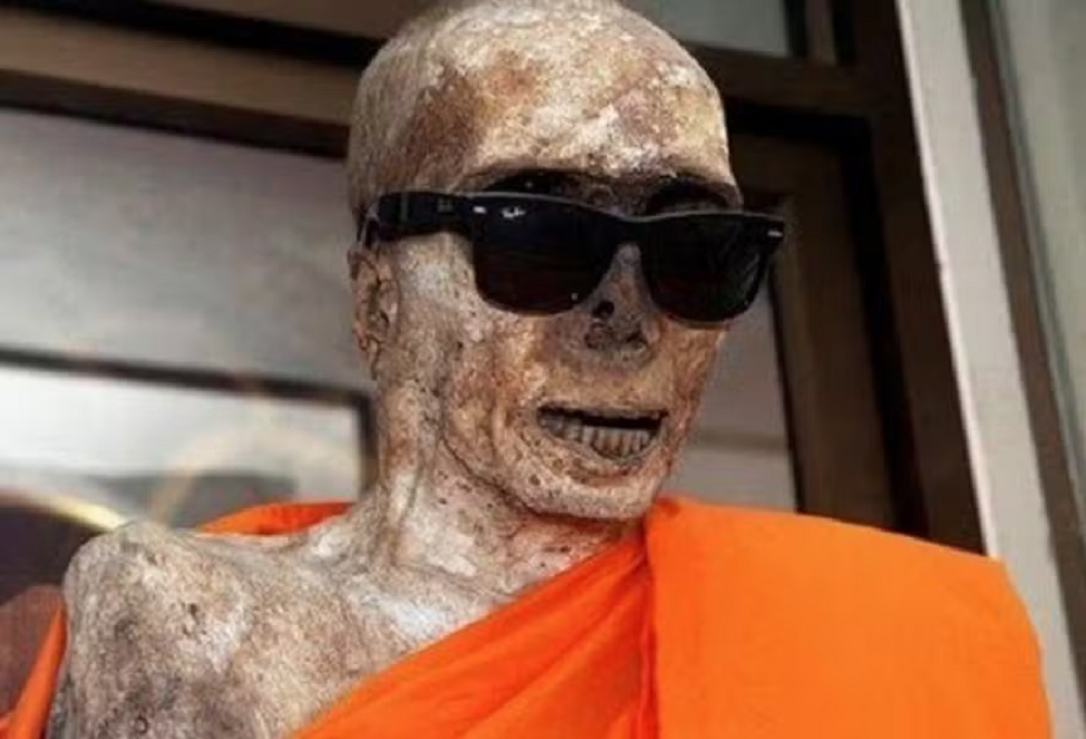 Monge budista que foi mumificado em templo no Japão, coberto com tecido laranja e óculos escuros