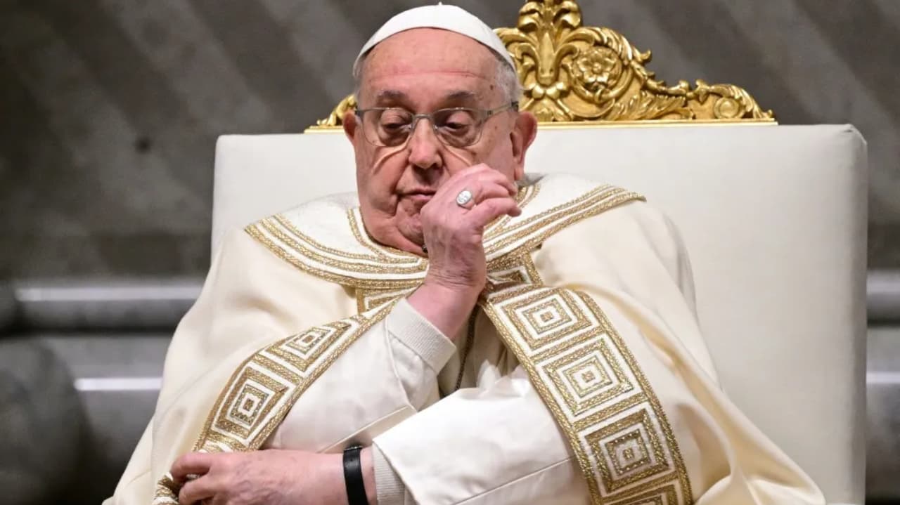 Papa Francisco sério, sentado, com uma das mãos próxima ao rosto