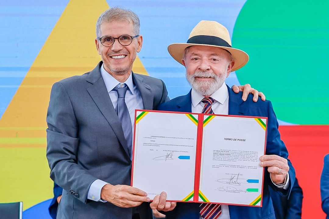 O ministro da Secretaria de Comunicação Social da Presidência, Sidônio Palmeira, e o presidente Lula (PT), sorrindo lado a lado e segurando ata de posse