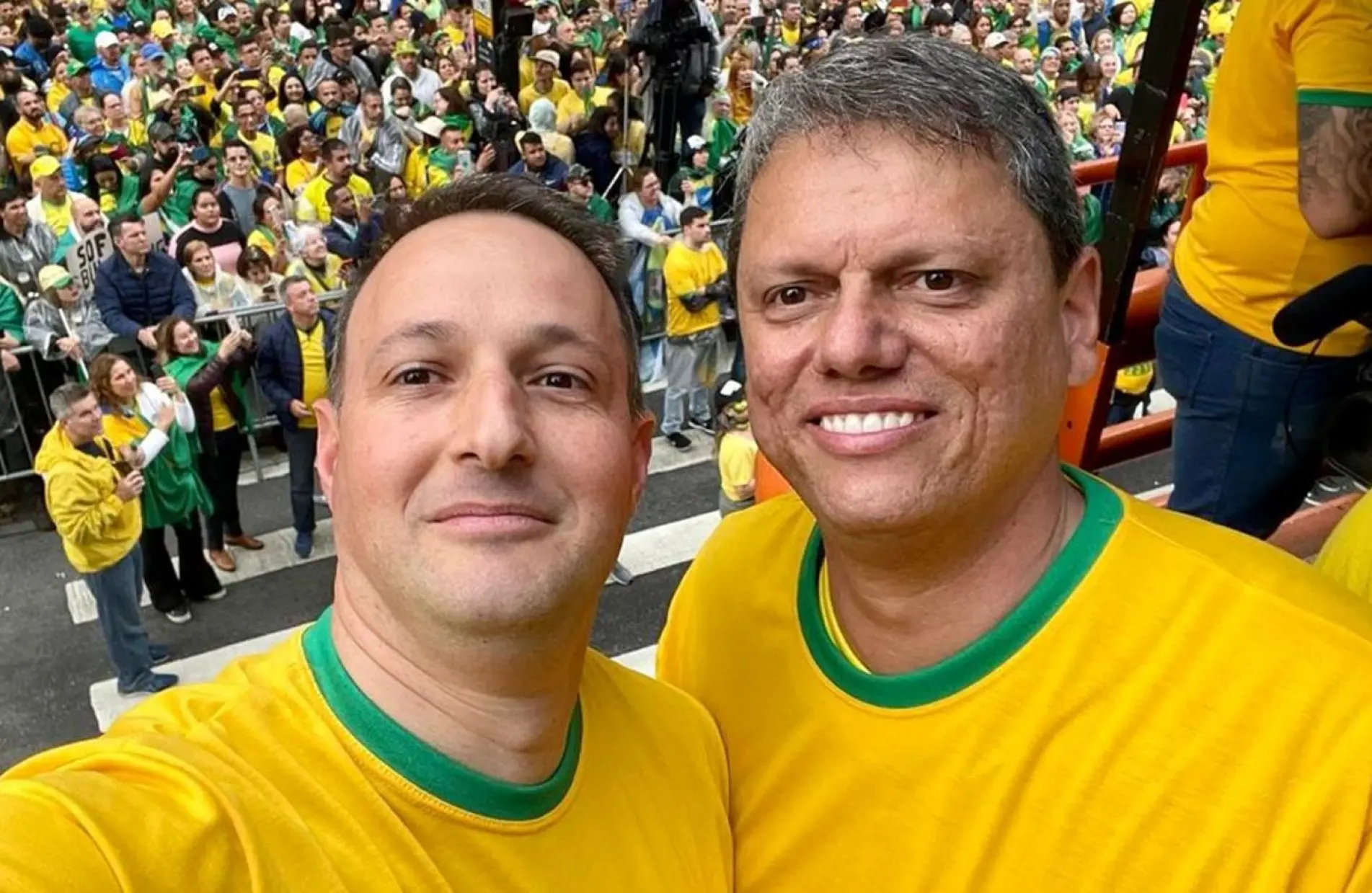 Guilherme Derrite e Tarcísio de Freitas sorrindo para foto, com camisetas amarelas e verdes os dois