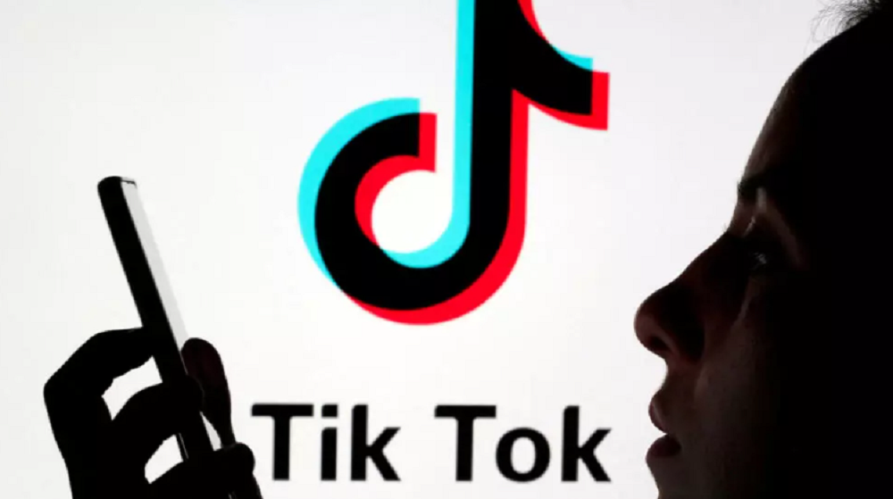 Logo do TikTok e sombra de pessoa olhando para o celular