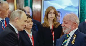 o russo Vladimir Putin em aperto de mãos com Lula, ambos se olhando e sorrindo