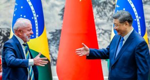 presidente do Brasil, Lula, e o presidente da China, Xi Jinping, se olhando, sorrindo, se preparando para aperto de mãos
