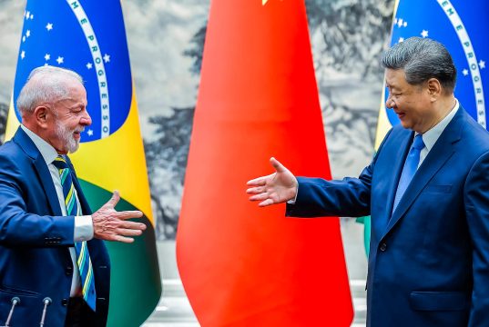 presidente do Brasil, Lula, e o presidente da China, Xi Jinping, se olhando, sorrindo, se preparando para aperto de mãos