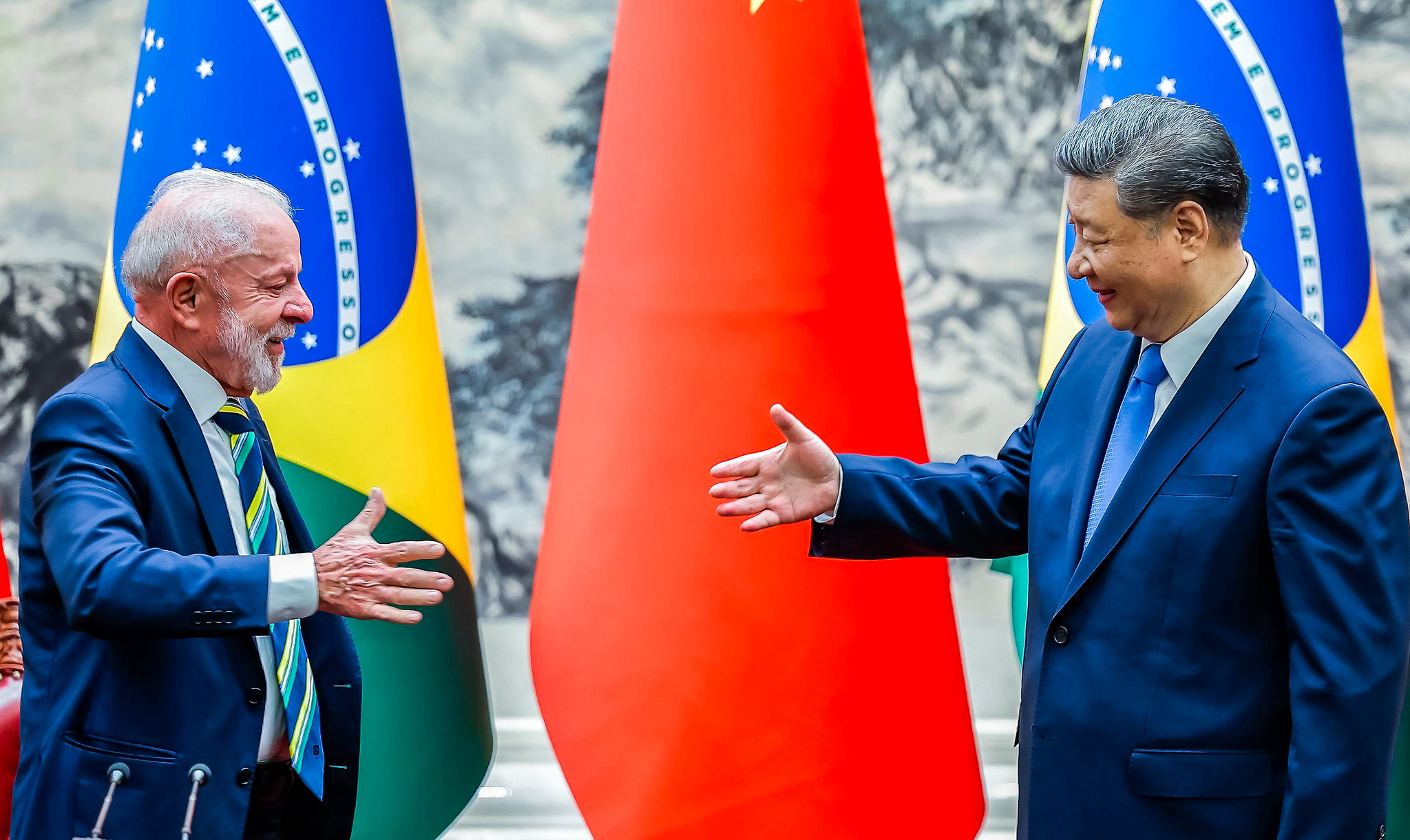 presidente do Brasil, Lula, e o presidente da China, Xi Jinping, se olhando, sorrindo, se preparando para aperto de mãos