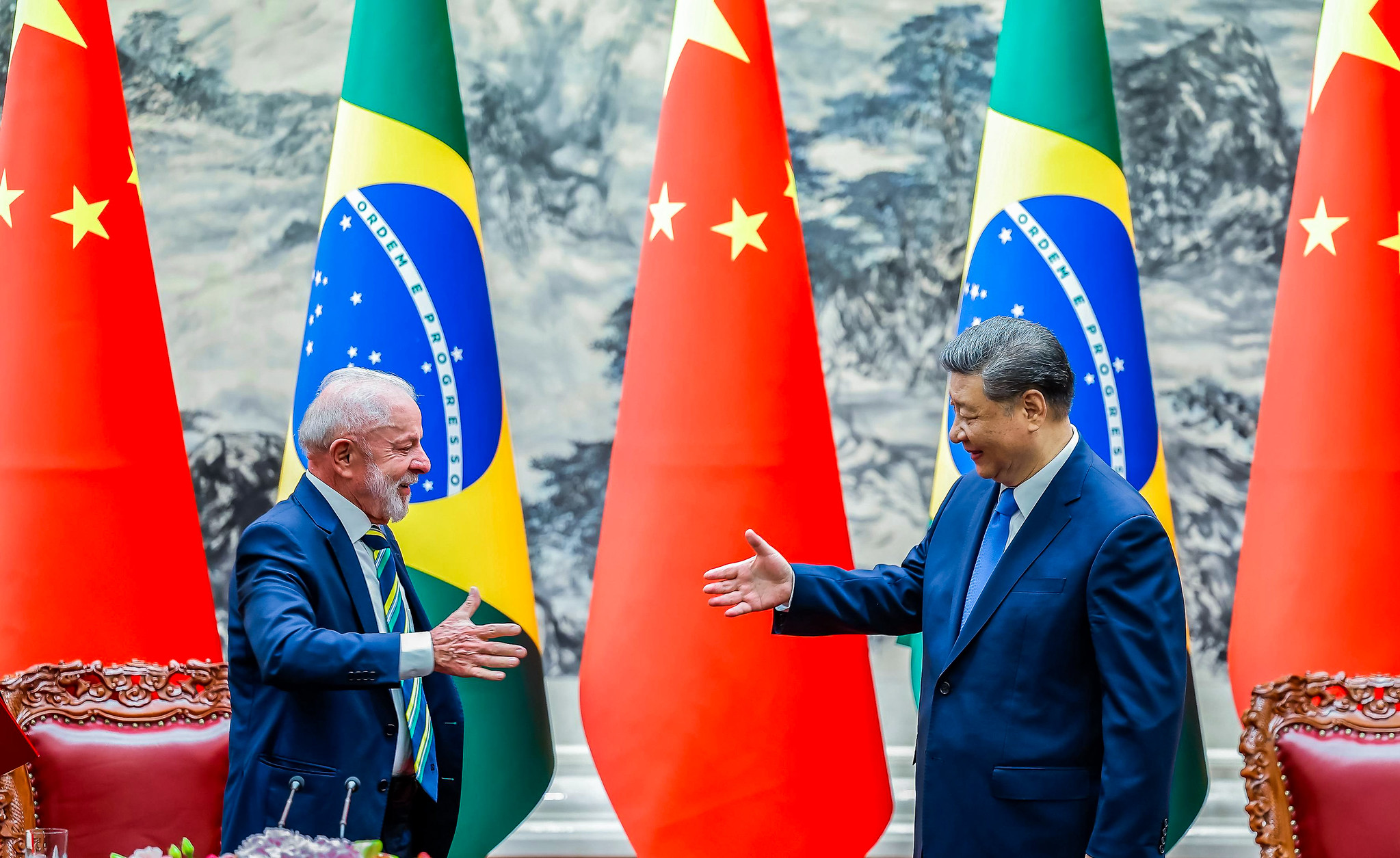 Lula com o presidente da China, Xi Jinping, prestes a dar aperto de mãos, ambos de perfil, em pé, se olhando