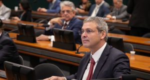 Lindbergh Farias sério, de óculos, olhando pra frente, sentado no plenário da Câmara dos Deputados
