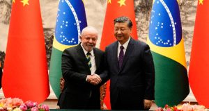 O presidente Lula e o chefe do governo chinês Xi Jinping em aperto de mãos, sorrindo para a câmera