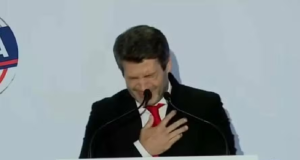 André Ventura com a mão no peito antes desmaiar, com expressão de dor e cabeça baixa
