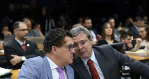 Deputados Alencar Santana e Lindbergh Farias sentados lado a lado, sérios, conversando