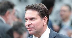deputado Delegado Ramagem (PL-RJ) de terno e gravata cinza, com camisa social branca, olhando para o lado com expressão confiante