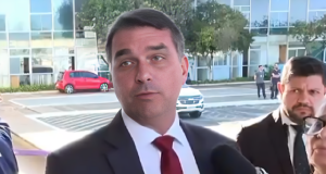 O senador Flávio Bolsonaro (PL-RJ) falando, sério, olhando para o lado, de terno e gravata