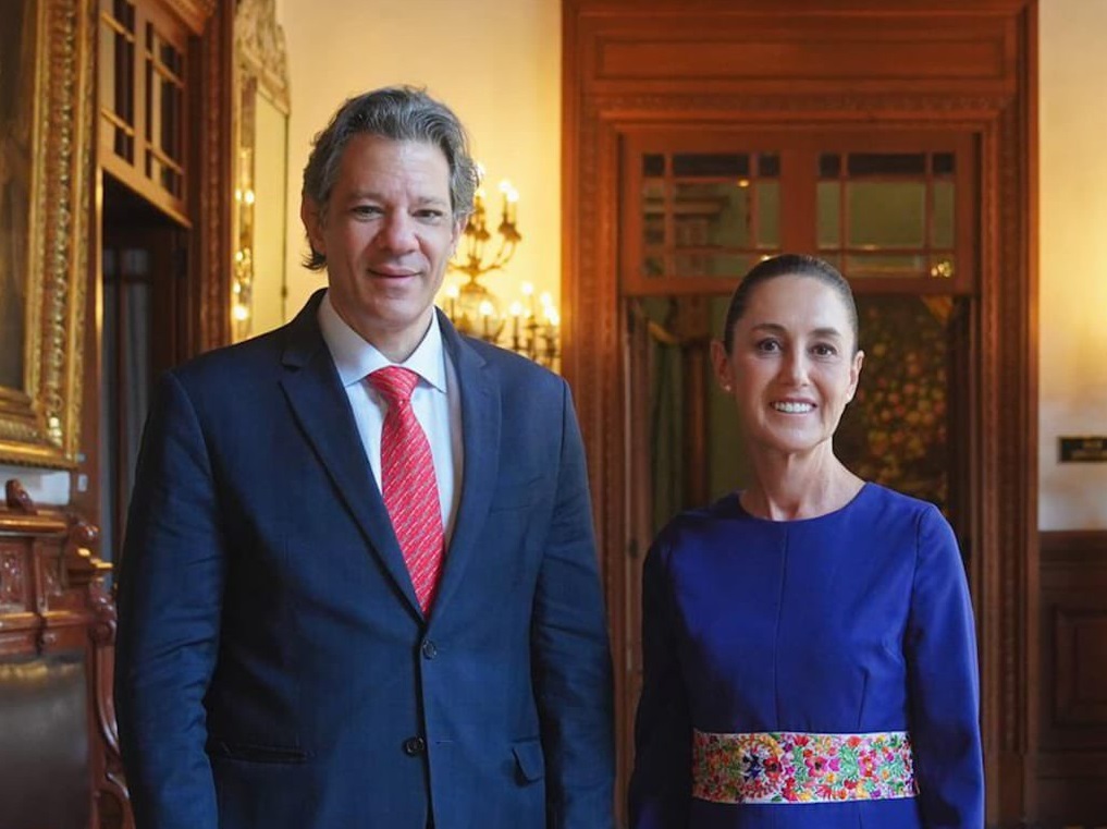 O ministro da Fazenda, Fernando Haddad, com a presidenta mexicana, Claudia Sheinbaum, ambos em pé, lado a lado, sorrindo para a câmera