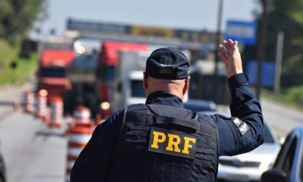 Polícia Rodoviária Federal (PRF) de costas, sinalizando para motoristas