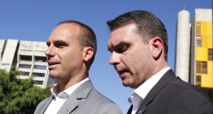 Eduardo Bolsonaro e Flávio, lado a lado, olhando pra frente sem olhar para a câmera, sérios