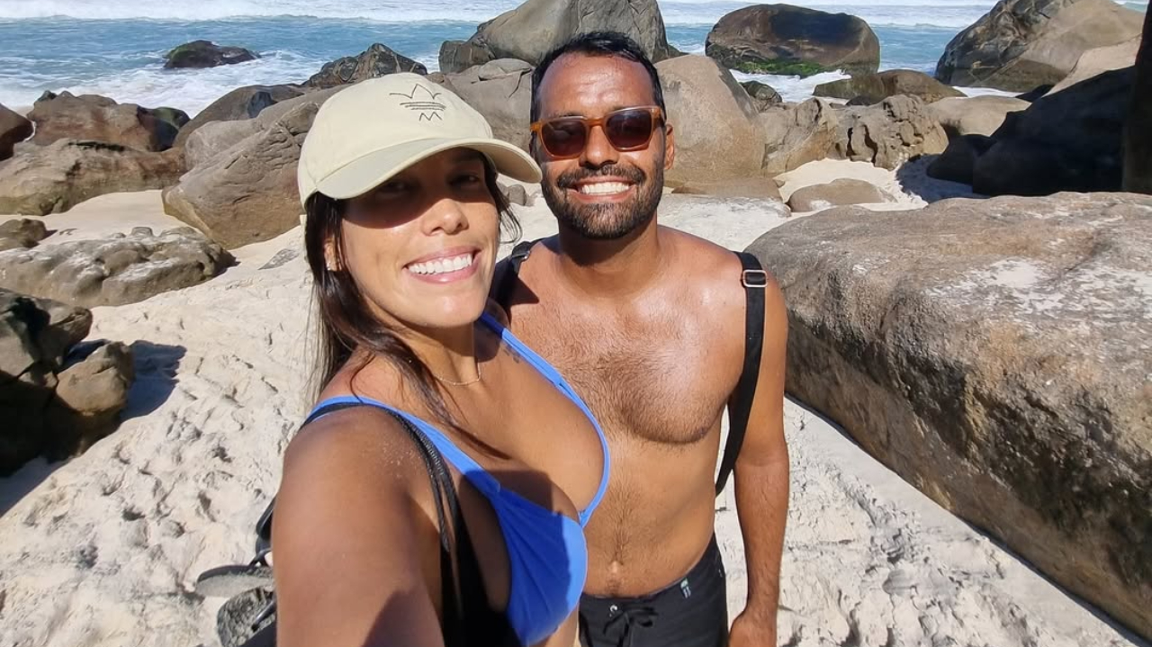 Conrado Santana e a namorada na praia, com roupas de banho