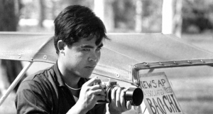 Nick Ut aos 20 anos em foto em preto e branco, com câmera na mão, olhando pra frente, sério