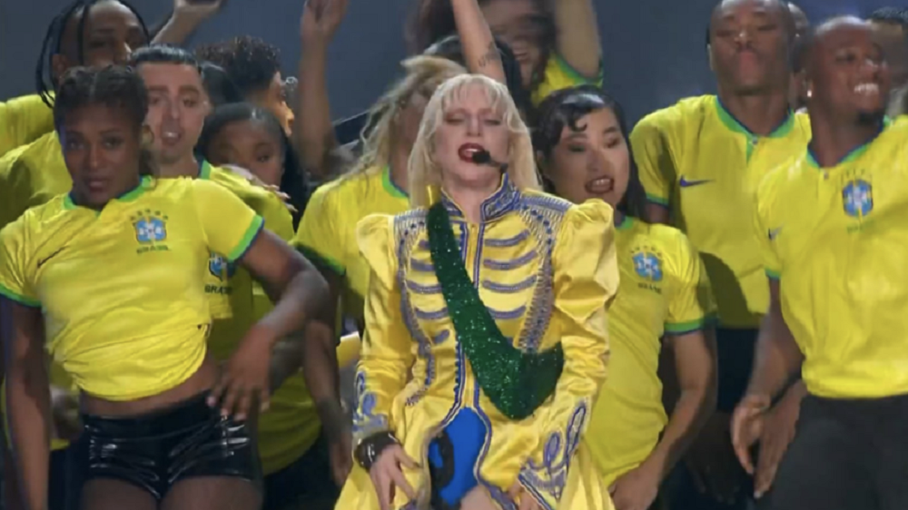 Lady Gaga e seus dançarinos se apresentando com look verde e amarelo