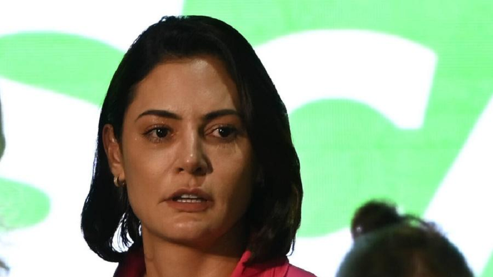 ex-primeira-dama Michelle Bolsonaro em close, com expressão assustada, de cabelo solto, sem olhar para a câmera