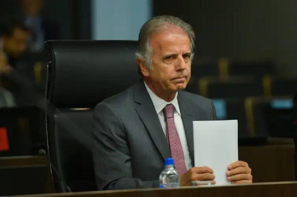 O ministro da Defesa, José Múcio, segurando papel, com expressão brava, olhando "de rabo de olho"