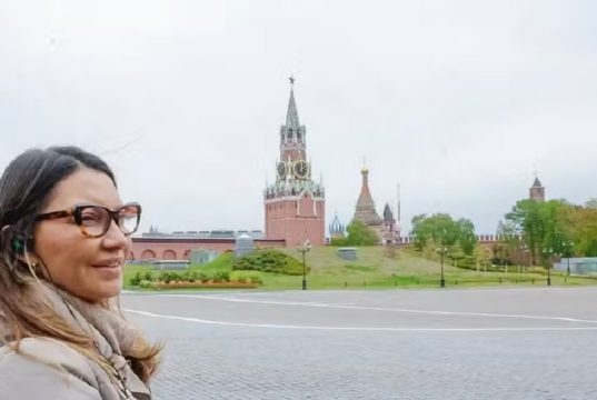 primeira-dama Janja da Silva no canto esquerdo de foto, de perfil, de cabelo solto e óculos de grau, na Rússia