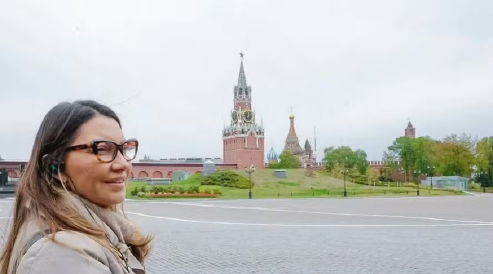 primeira-dama Janja da Silva no canto esquerdo de foto, de perfil, de cabelo solto e óculos de grau, na Rússia