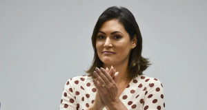 Michelle Bolsonaro de cabelo solto e roupa clara, batendo palmas
