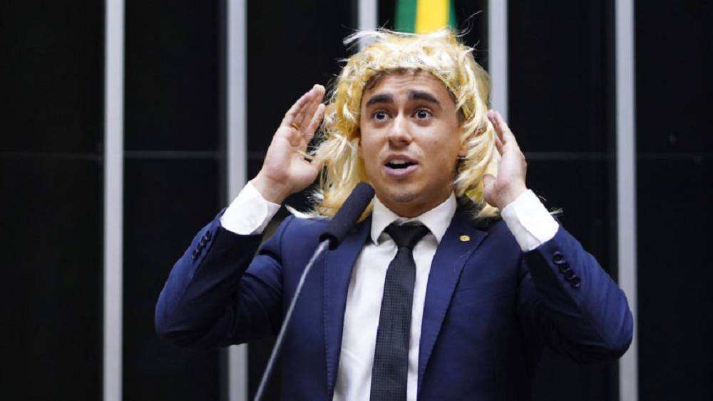 deputado Nikolas Ferreira (PL-MG) de peruca no plenário da Câmara, falando, com as mãos próximas à cabeça
