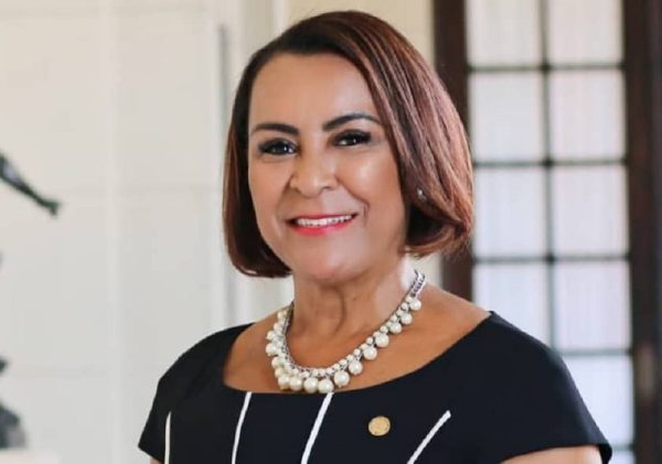 deputada estadual Tia Ju (Republicanos) de roupa preta e colar de pérolas, sorrindo para a câmera, de batom vermelho e cabelo solto curto