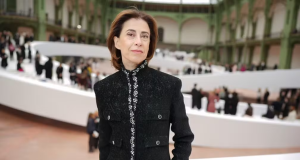 Fernanda Torres de roupa preta, posando em pé, séria, de cabelo solto