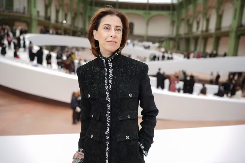 Fernanda Torres de roupa preta, posando em pé, séria, de cabelo solto