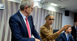 ministra do Meio Ambiente e Mudanças Climáticas, Marina Silva, de roupa bege e cabelo preso, em pé, apontando e falando, sem olhar para a câmera