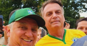 O senador Izalci Lucas (PL) e o ex-presidente Jair Bolsonaro (PL) sorrindo para selfie, lado a lado, com camisetas amarelas e verdes, o senador de boné
